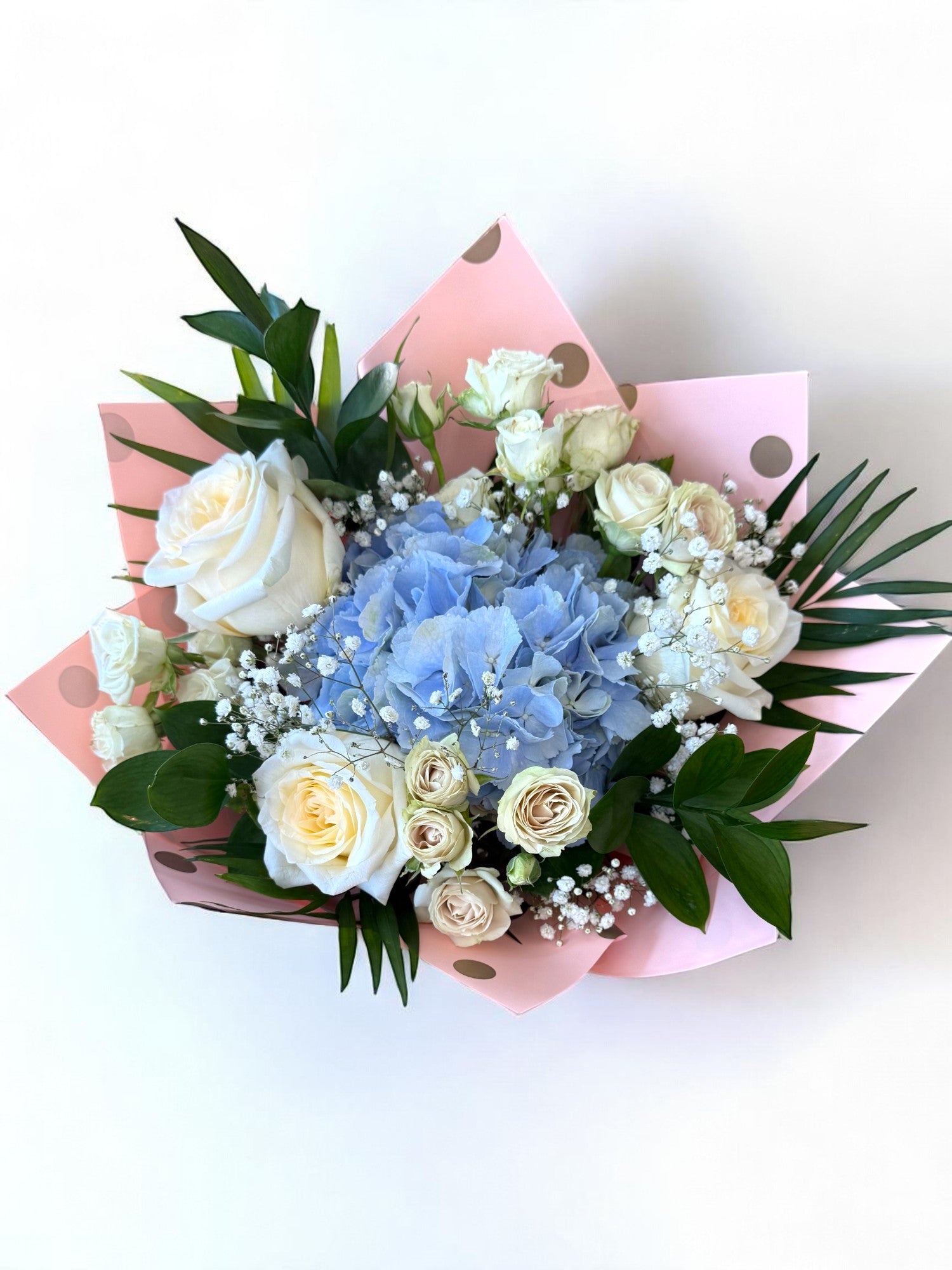 Buchet cu hortensie albastră și trandafiri albi, ambalaj roz, vedere de sus